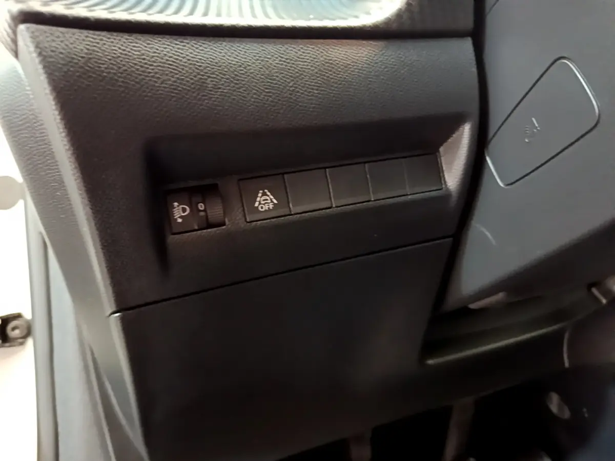 Gros plan sur les commandes noires côté gauche du tableau de bord d'une Peugeot 208 blanche, version Allure Business.