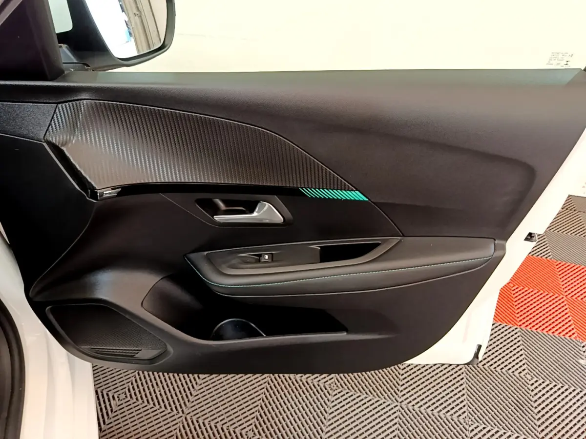 Gros plan sur la porte avant gauche blanche d'une Peugeot 208 2020 avec garniture noire et surpiqûres bleues.
