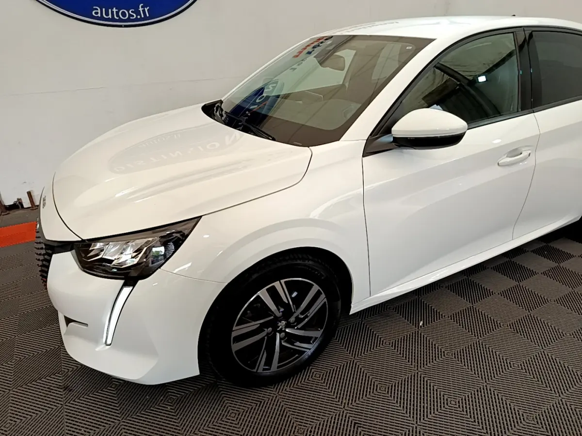 Peugeot 208 blanc vue 3/4 avant droit, avec phares LED et jantes alliage noires distinctives.