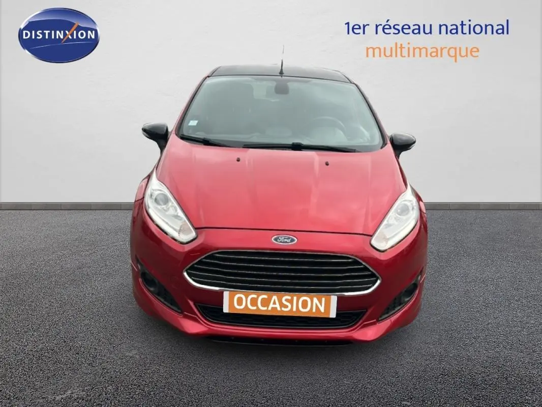 Vue avant d'une Ford Fiesta rouge 2017 avec calandre chromée et phares allumés, affichant une plaque "OCCASION".