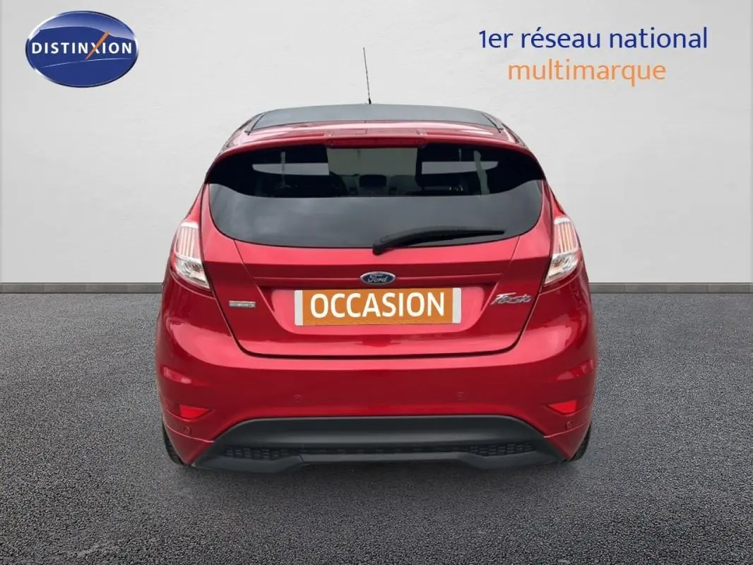 Vue arrière d'une Ford Fiesta rouge 2017 avec vitres surteintées et logo "Occasion" sur le coffre.