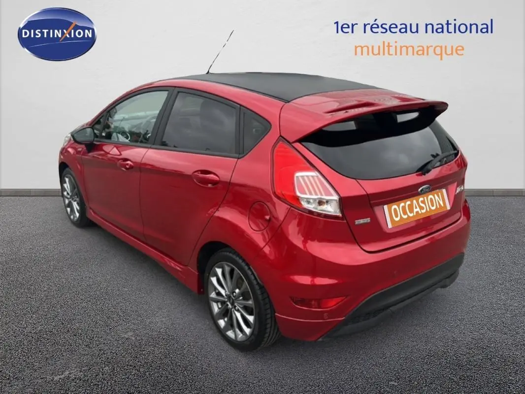 Ford Fiesta rouge vue 3/4 arrière droit, avec toit noir, vitres surteintées et jantes alliage 16 pouces.
