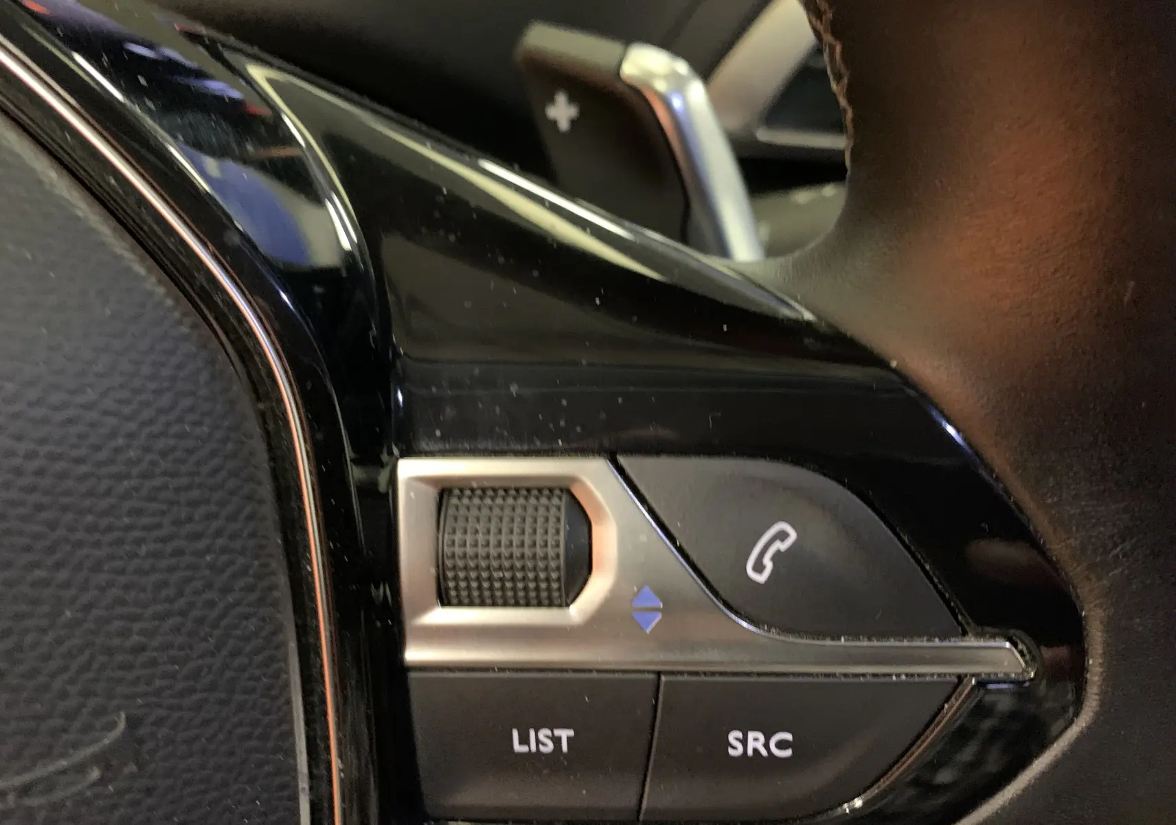 Gros plan sur les commandes de volume et téléphone au volant en cuir noir d'un Peugeot 3008 2020.