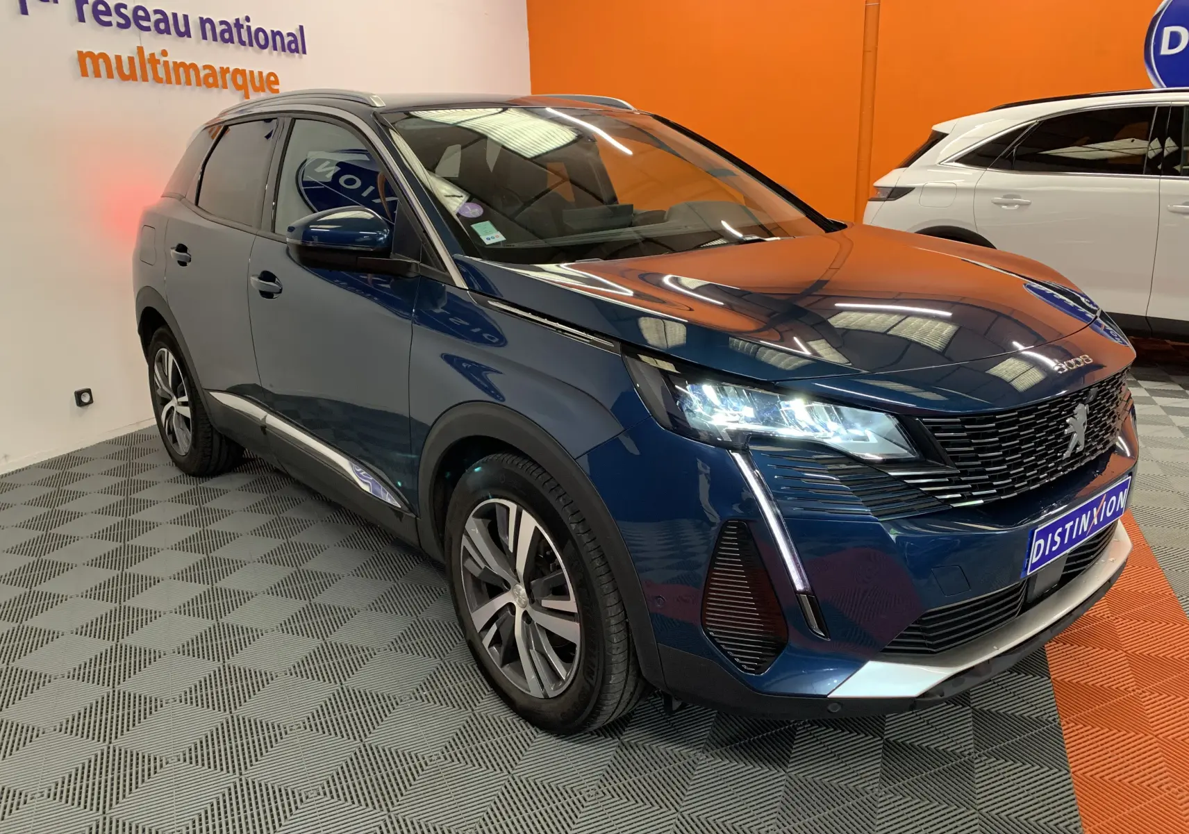 Peugeot 3008 bleu Célèbes en 3/4 avant droit, phares LED allumés, calandre noire et jantes alliage visibles.