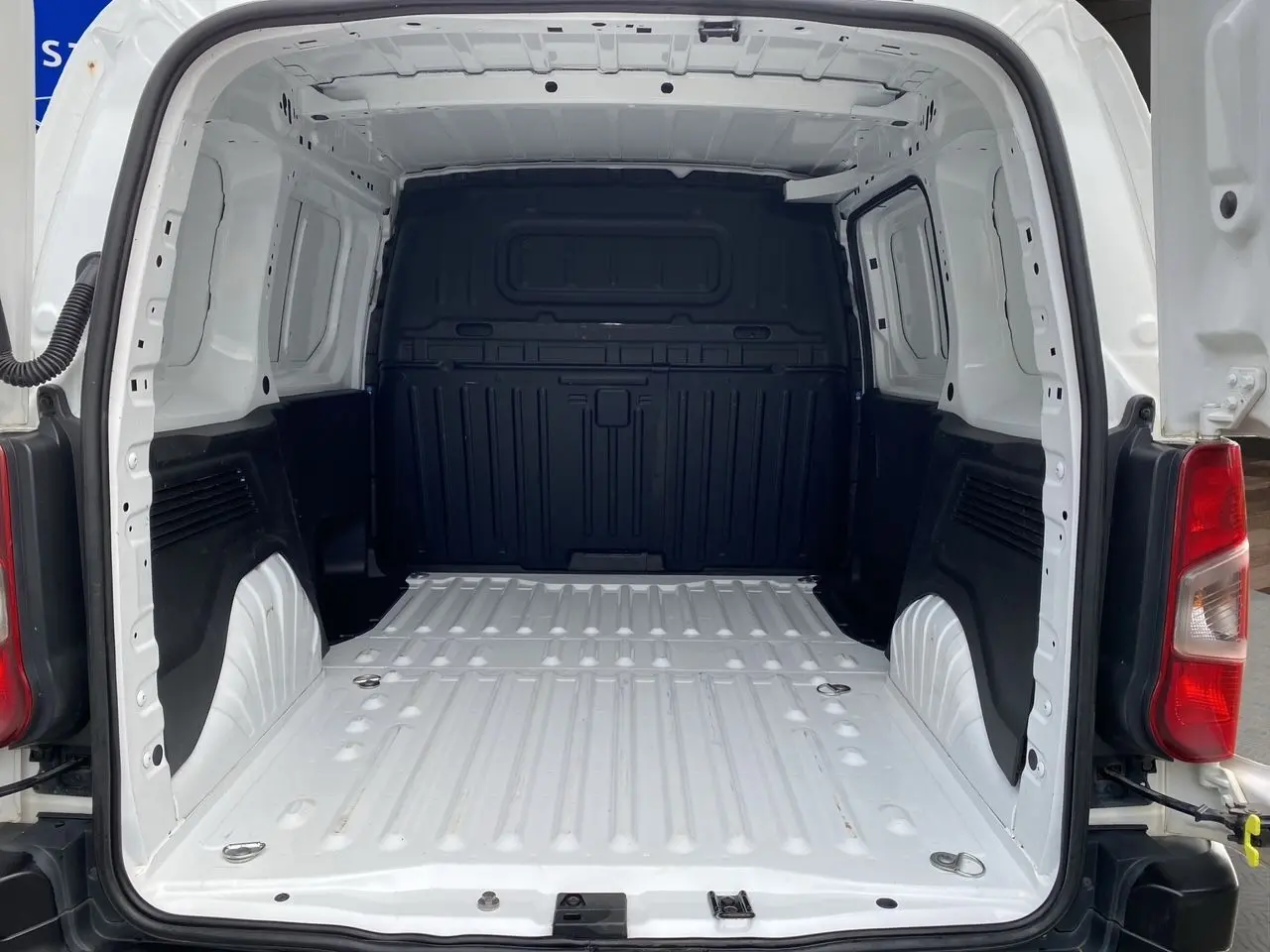 Vue arrière du fourgon Citroën Berlingo blanc 2019, montrant l'espace de chargement vide avec parois noires.