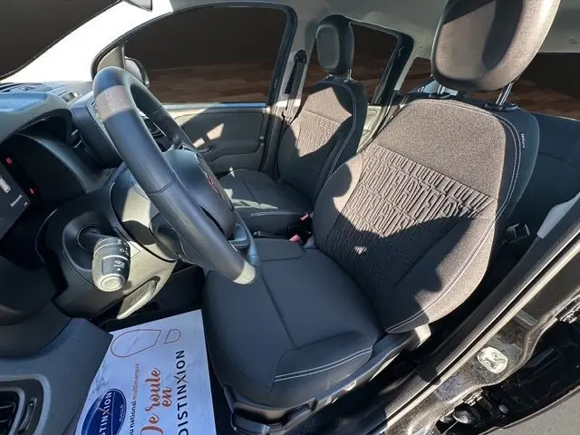 Vue intérieure côté conducteur de la Fiat Panda noire 2025, sièges tissu noir avec motifs et volant multifonction.