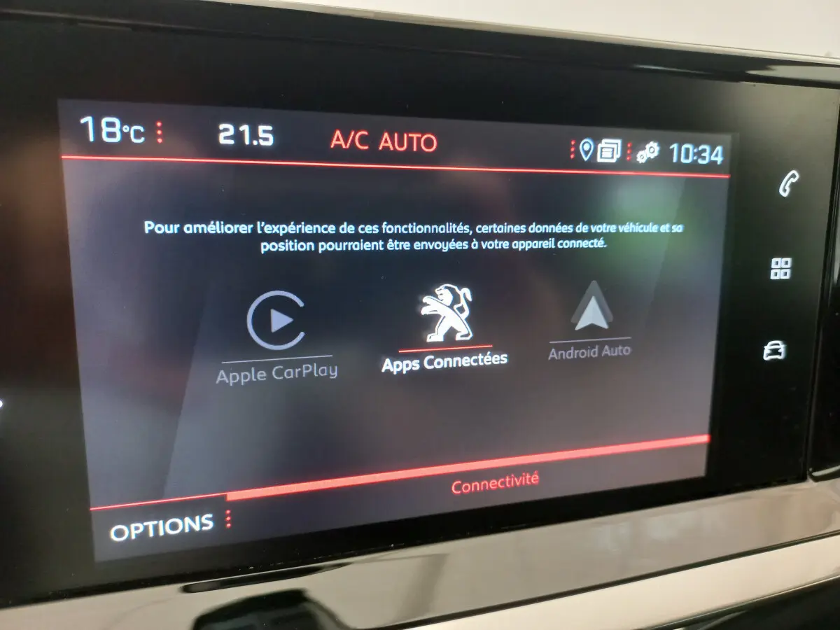 Écran tactile central de la Peugeot 208 blanche PureTech 100 S&S Allure affichant les options Apple CarPlay et Android Auto.