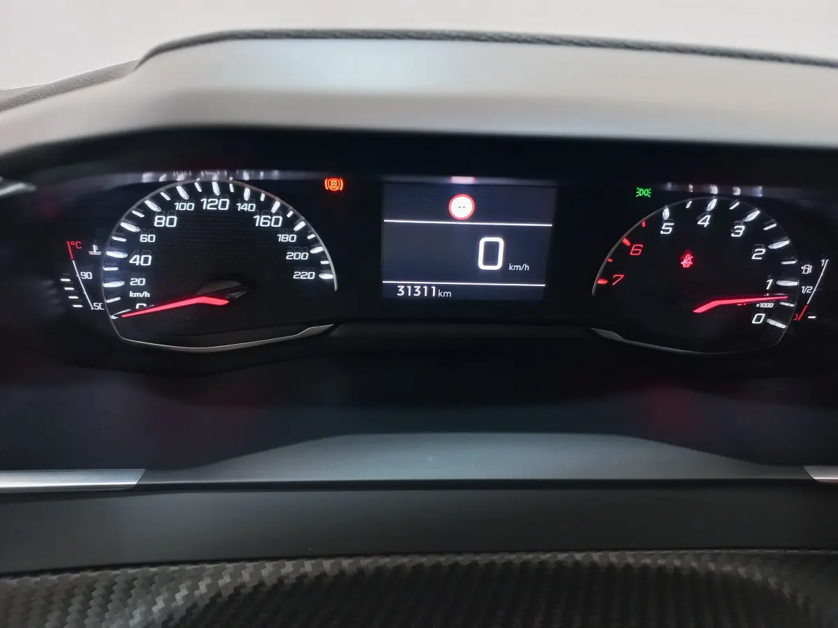 Vue rapprochée du tableau de bord numérique de la Peugeot 208 blanche, affichant 0 km/h et 31 311 km au compteur.