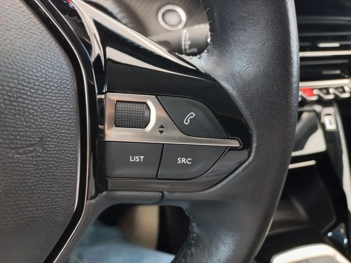 Gros plan sur les commandes du volant cuir noir de la Peugeot 208 PureTech 100 S&S Allure 2021.
