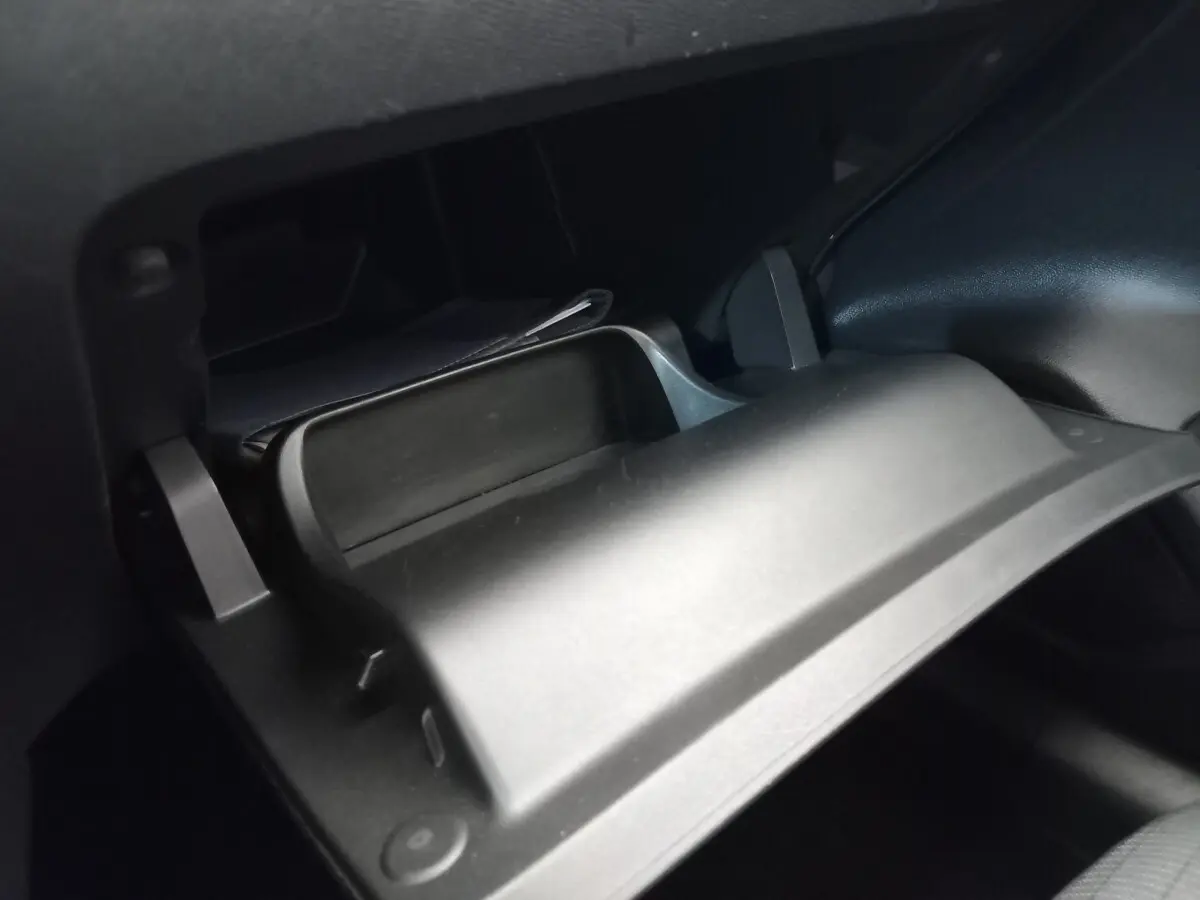 Gros plan sur la boîte à gants ouverte du Peugeot 208 PureTech 100 S&S Allure blanc, intérieur noir.