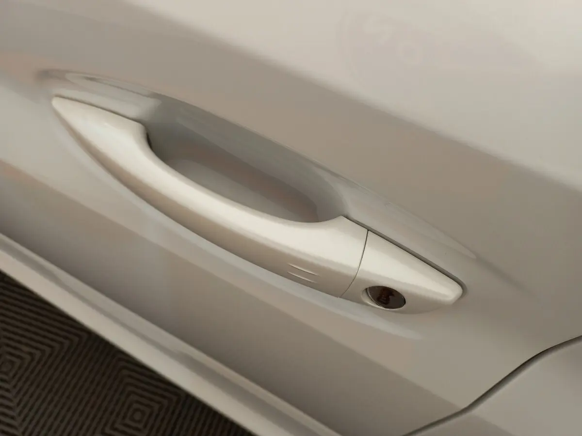 Poignée de porte blanche en gros plan sur le côté droit d'une Peugeot 208 PureTech 100 S&S Allure 2021.