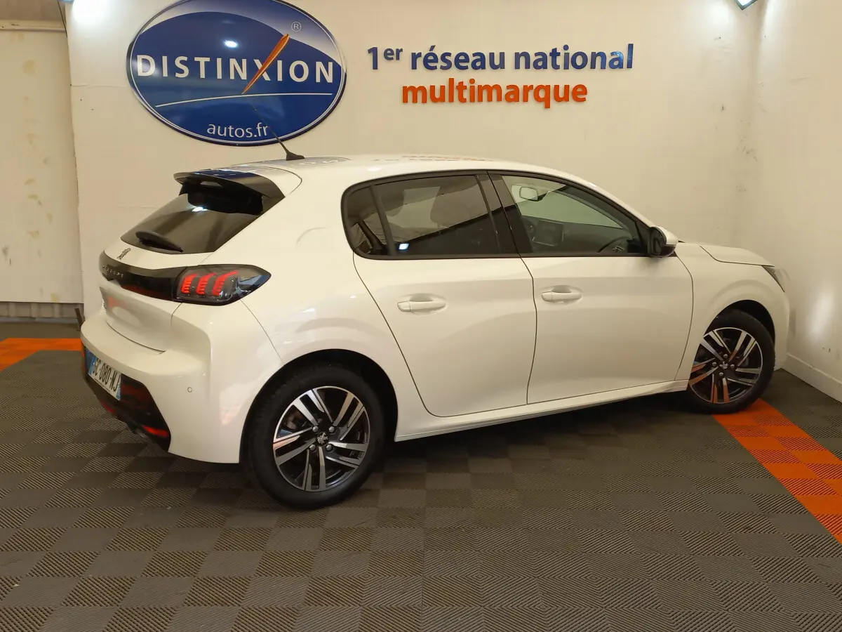 Vue côté droit arrière d'une Peugeot 208 blanche PureTech 100 S&S Allure avec feux LED et jantes alliage modernes.