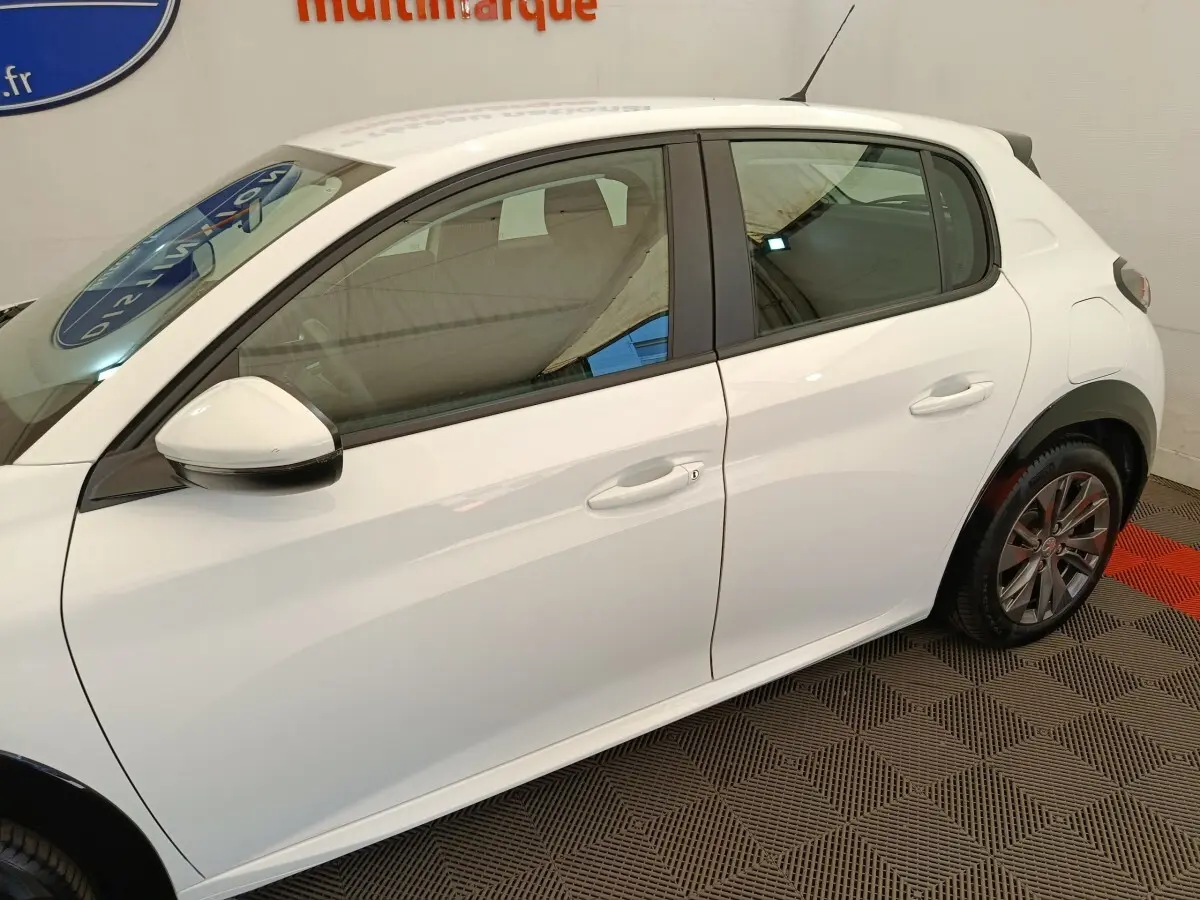 Vue de profil côté gauche d'une Peugeot 208 électrique Active Business R blanche, avec rétroviseur blanc et jantes alliage.