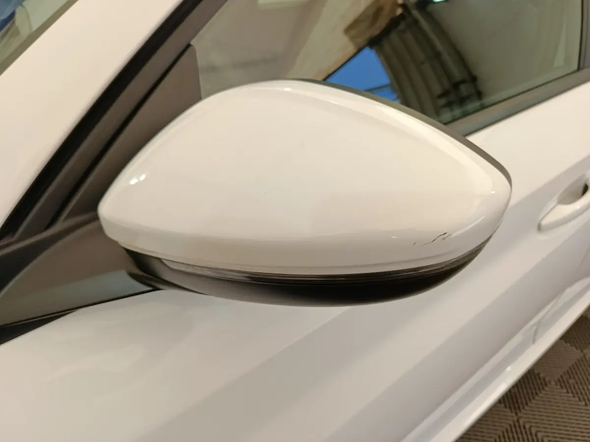 Rétroviseur côté gauche blanc de Peugeot 208 électrique 2021, vue rapprochée avec portière et poignée visibles.