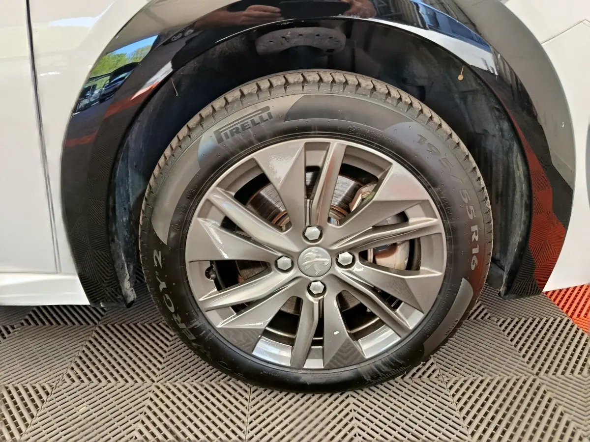 Gros plan sur la roue avant droite de la Peugeot 208 électrique blanche, jante alliage et pneu Pirelli.