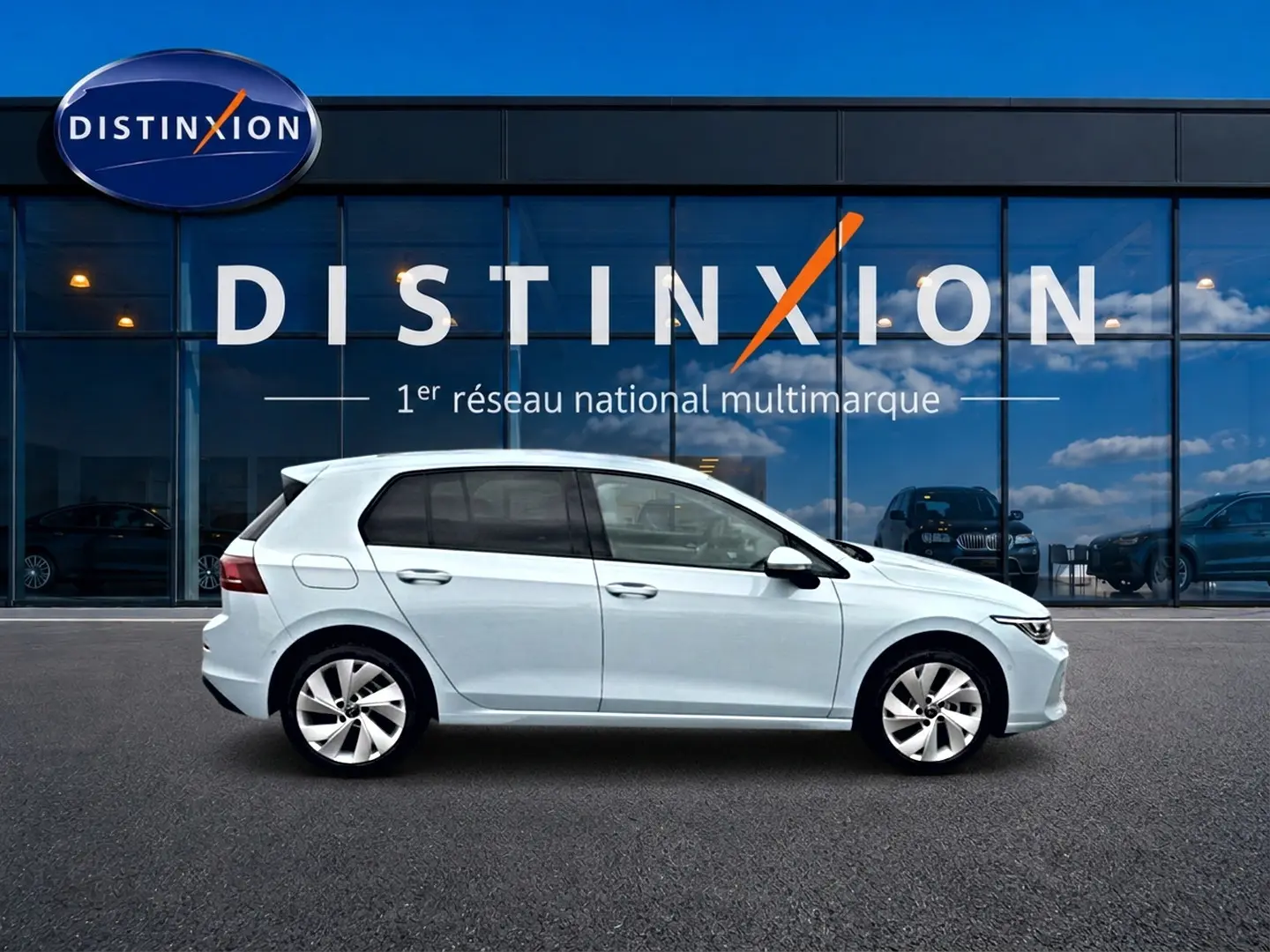 Profil droit d'une Volkswagen Golf 1.5 etsi evo2 116 life dsg7 bleu glacier devant une vitrine Distinxion.