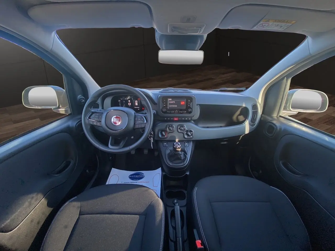Intérieur de la Fiat Panda 2025 vue de face, tableau de bord noir avec écran multimédia et volant multifonction.