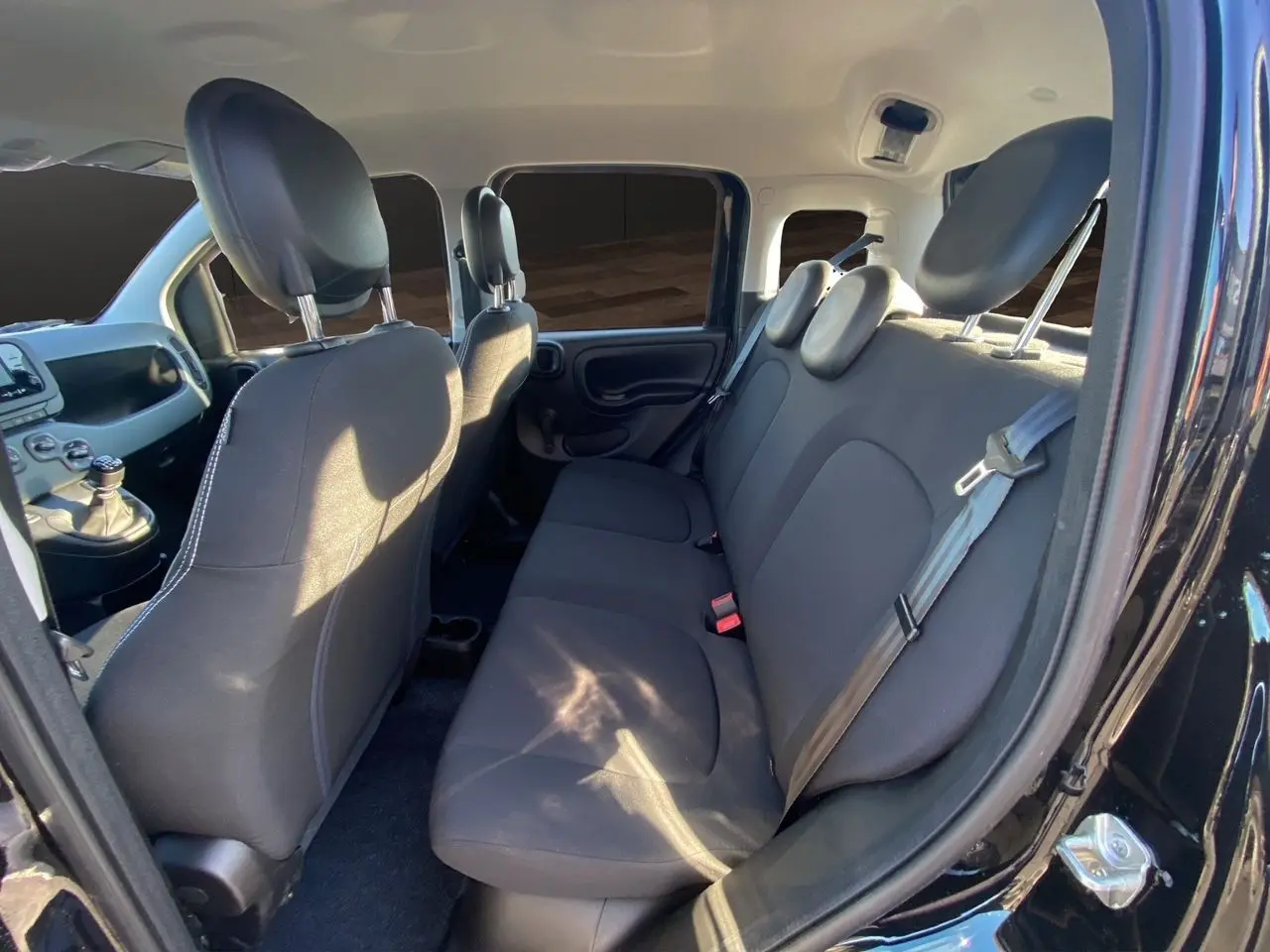 Vue intérieure côté droit montrant les sièges arrière noirs et une partie de l'avant de la Fiat Panda noire 2025.