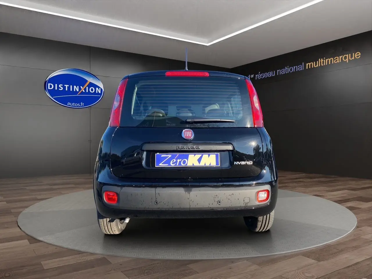 Vue arrière d'une FIAT Panda noire 2025 avec logo Hybrid et plaque Zero KM, en showroom lumineux.