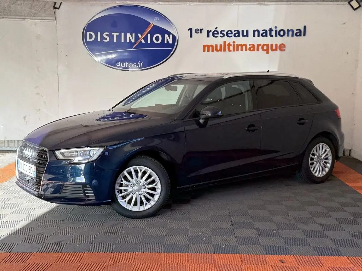 Audi A3 2.0 TDI bleu vue de profil côté gauche dans un showroom avec logo Distinxion en arrière-plan