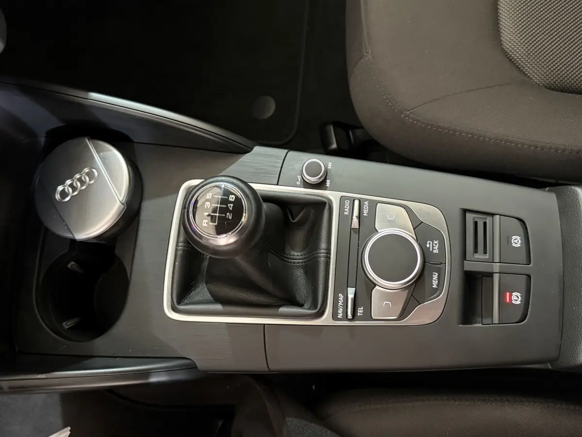 Vue rapprochée de la console centrale noire de l'Audi A3 2.0 TDI 2018 avec levier de vitesse manuel et commandes multimédia.