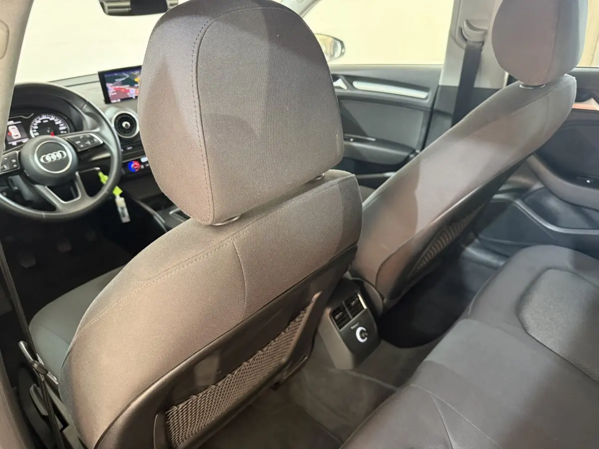 Vue intérieure arrière de l'Audi A3 Business Line 2018, sièges tissu gris et tableau de bord avec écran central.