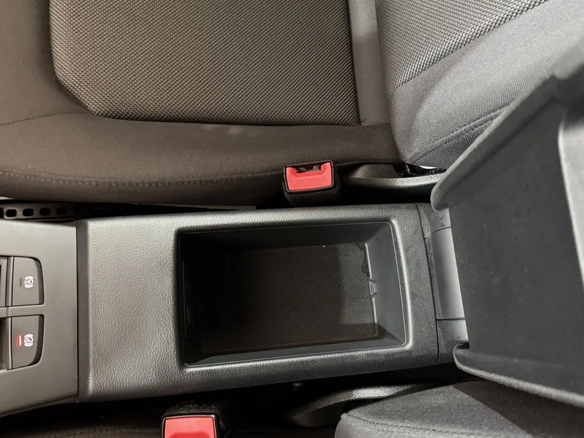 Vue plongeante sur la console centrale noire entre les sièges avant gris foncé d'une Audi A3 bleu 2018.