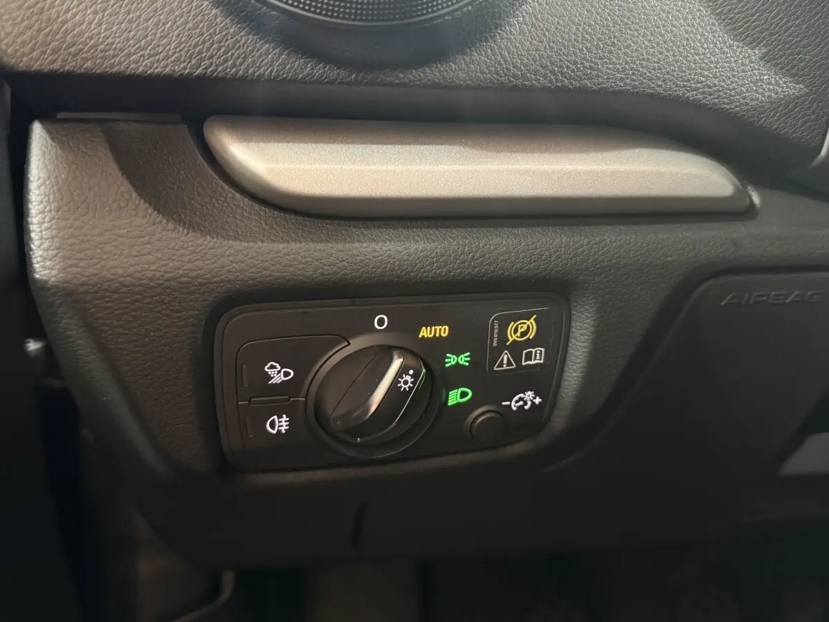 Gros plan sur la commande des phares avec réglage automatique dans l'habitacle noir de l'Audi A3 bleu 2018.