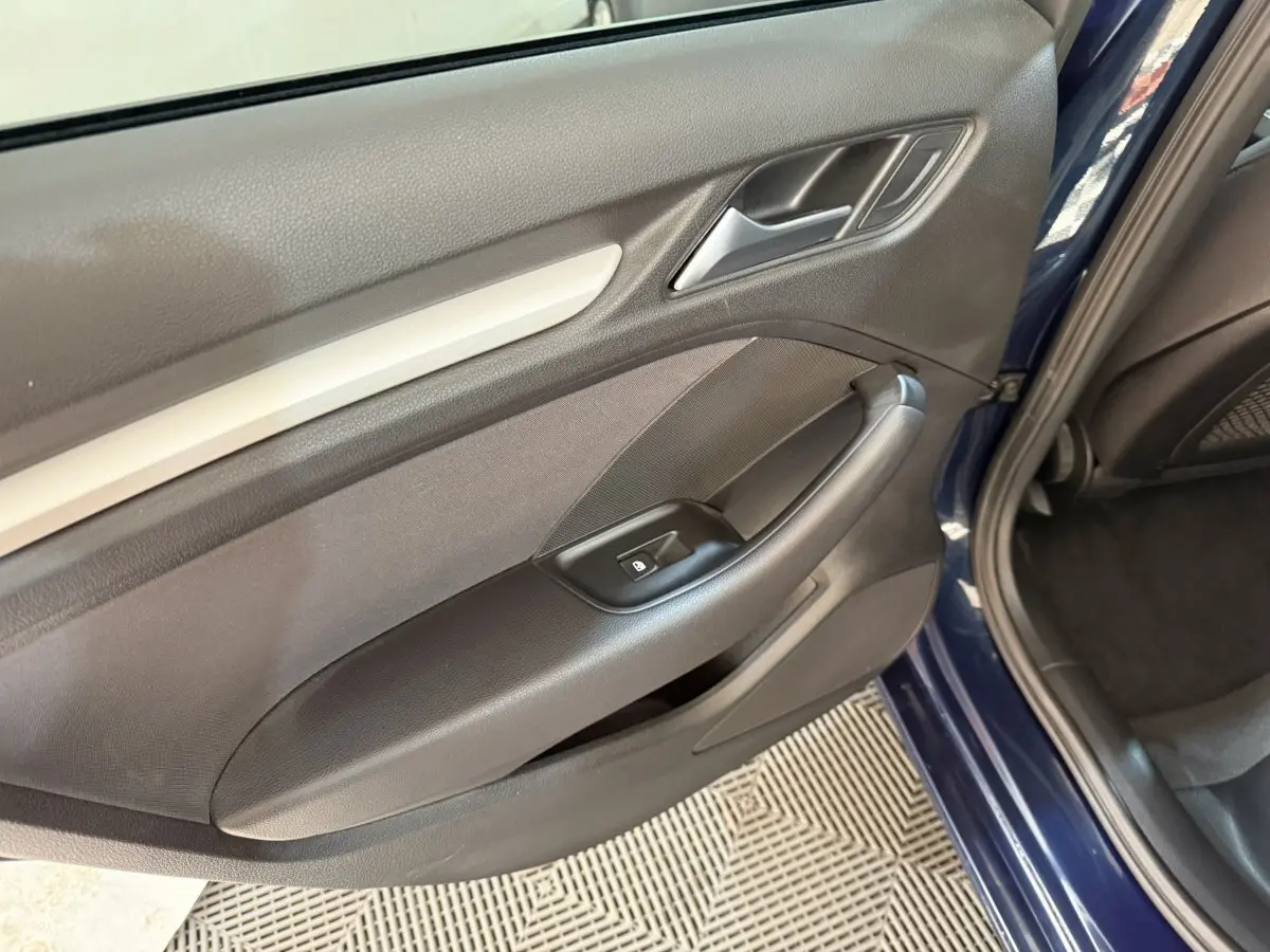 Vue rapprochée de la porte arrière droite bleu foncé d’une Audi A3 2.0 TDI 2018 avec accoudoir et commande de lève-vitre.