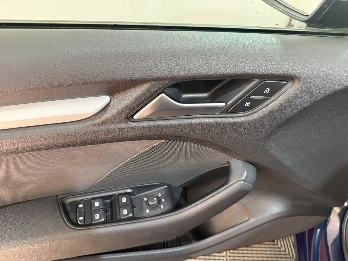 Vue rapprochée de la porte avant gauche bleu foncé de l'Audi A3 2.0 TDI 2018 avec commandes de vitres et serrure.