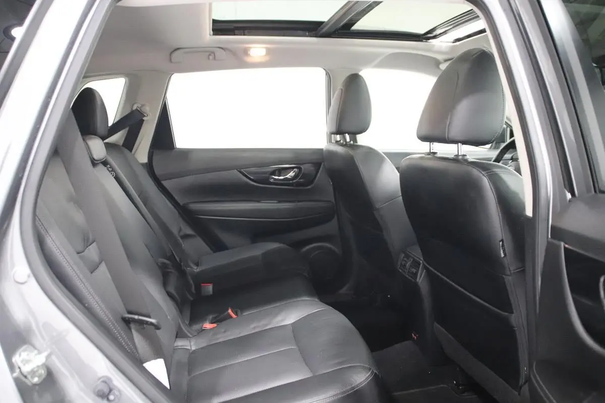 Vue intérieure côté gauche du Nissan X-TRAIL 2021 gris métallisé, montrant les sièges arrière en cuir et le toit ouvrant panoramique.