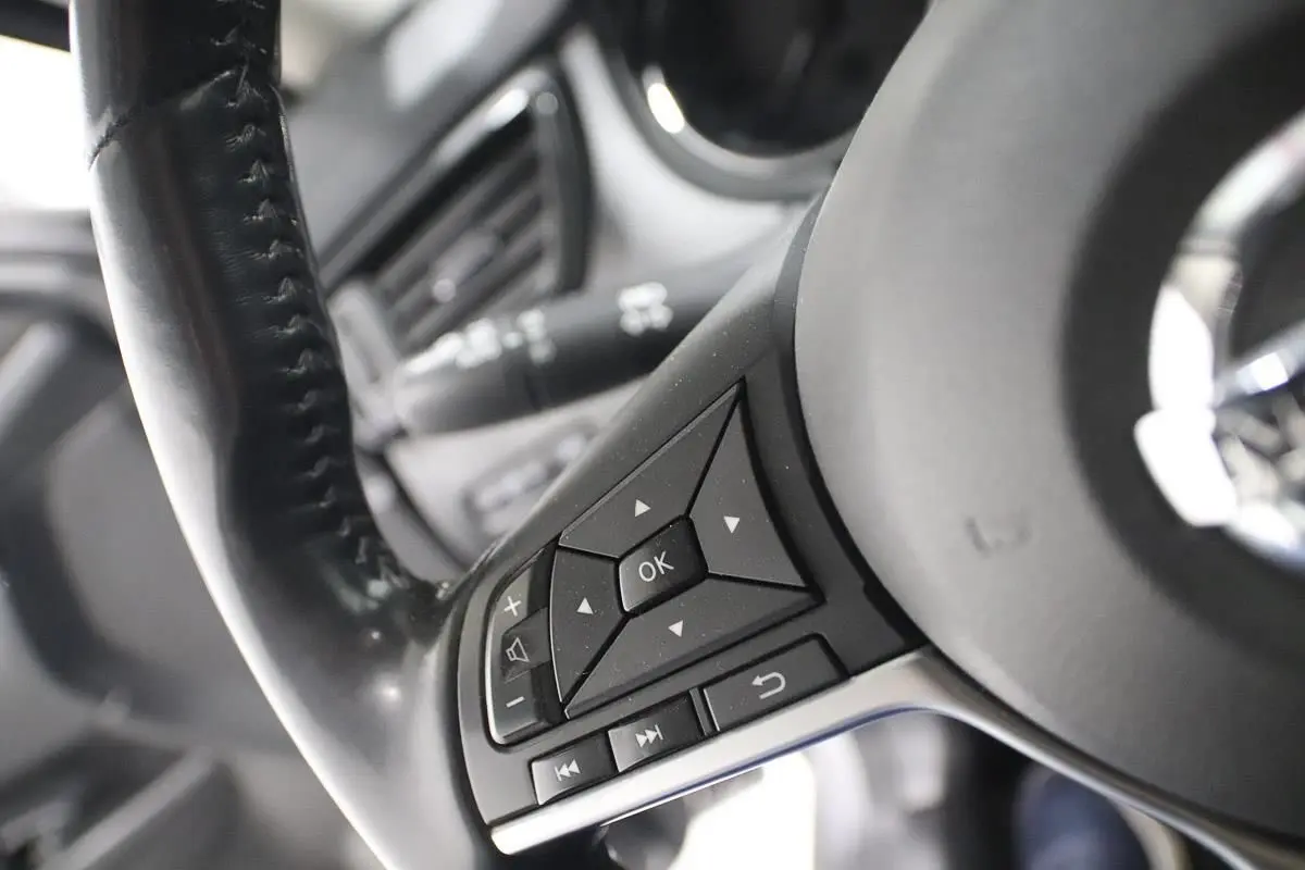 Gros plan sur les commandes au volant en cuir noir du Nissan X-Trail gris métallisé, côté gauche.