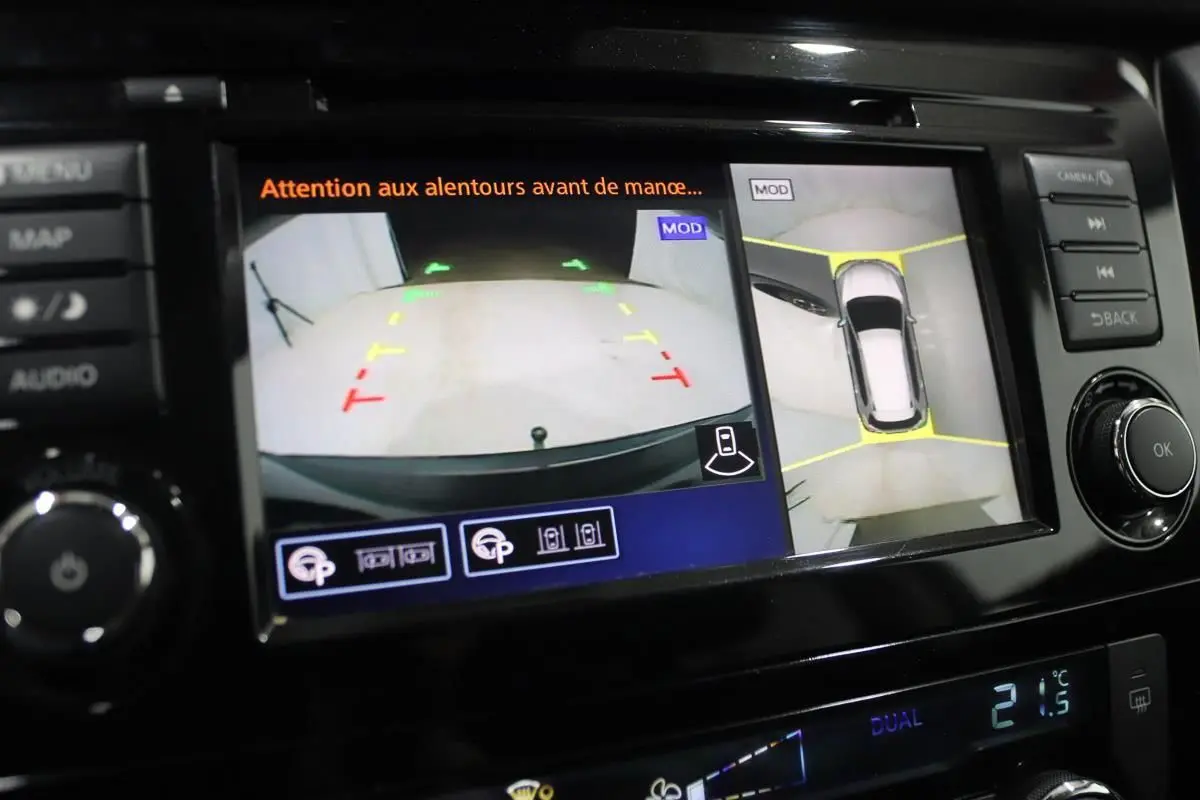 Écran de caméra 360° et recul affichant l’environnement autour d’un Nissan X-Trail gris métallisé.