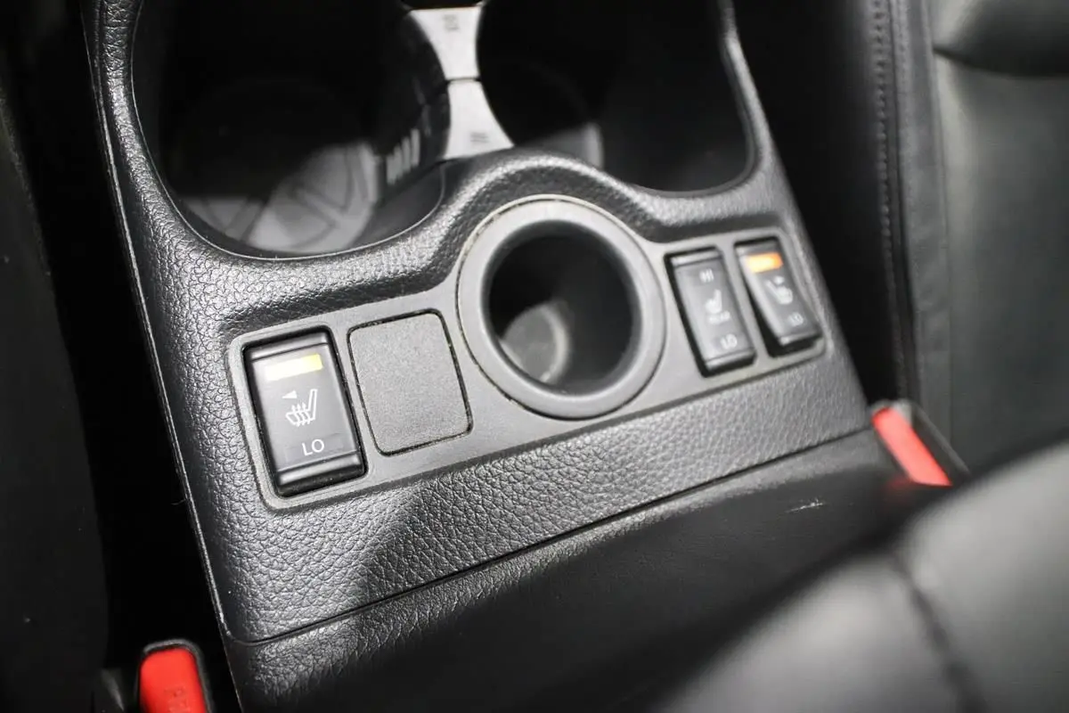 Gros plan sur les commandes des sièges chauffants en cuir noir du Nissan X-Trail 1.7 D 150, console centrale.