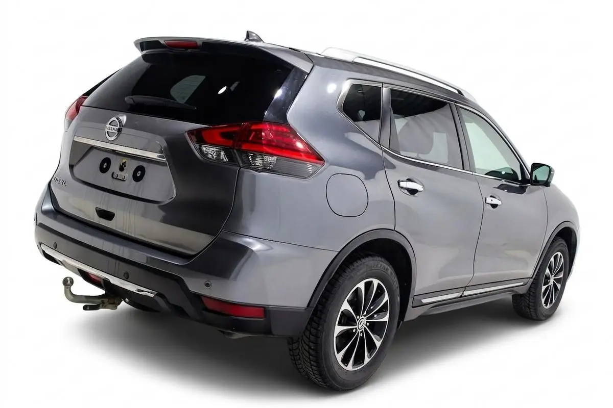 Vue 3/4 arrière droite d'un Nissan X-Trail gris métallisé avec attelage et toit ouvrant visible.