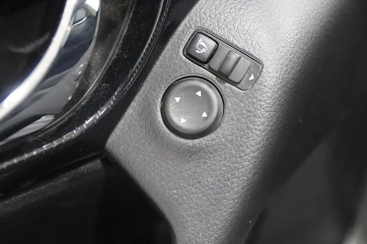 Gros plan sur les commandes de réglage des rétroviseurs intérieurs en plastique noir du Nissan X-Trail 1.7 D 150 gris métallisé.