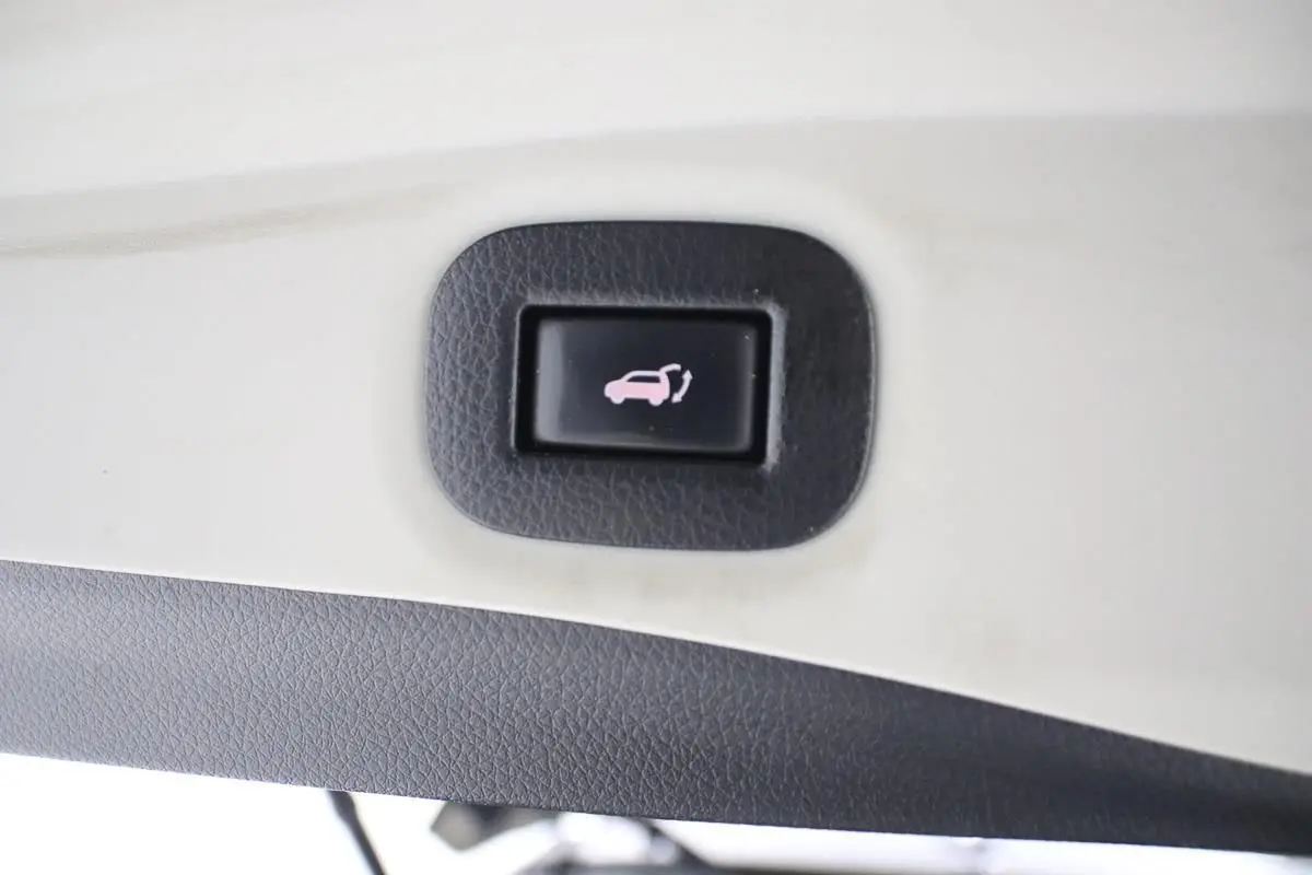 Bouton d'ouverture électrique du hayon sur le panneau intérieur d'un Nissan X-Trail gris métallisé.