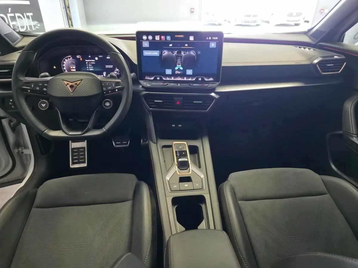 Vue intérieure avant du CUPRA Formentor 1.5 eTSI Hybrid 2025, tableau de bord noir avec écran tactile central et volant sport.