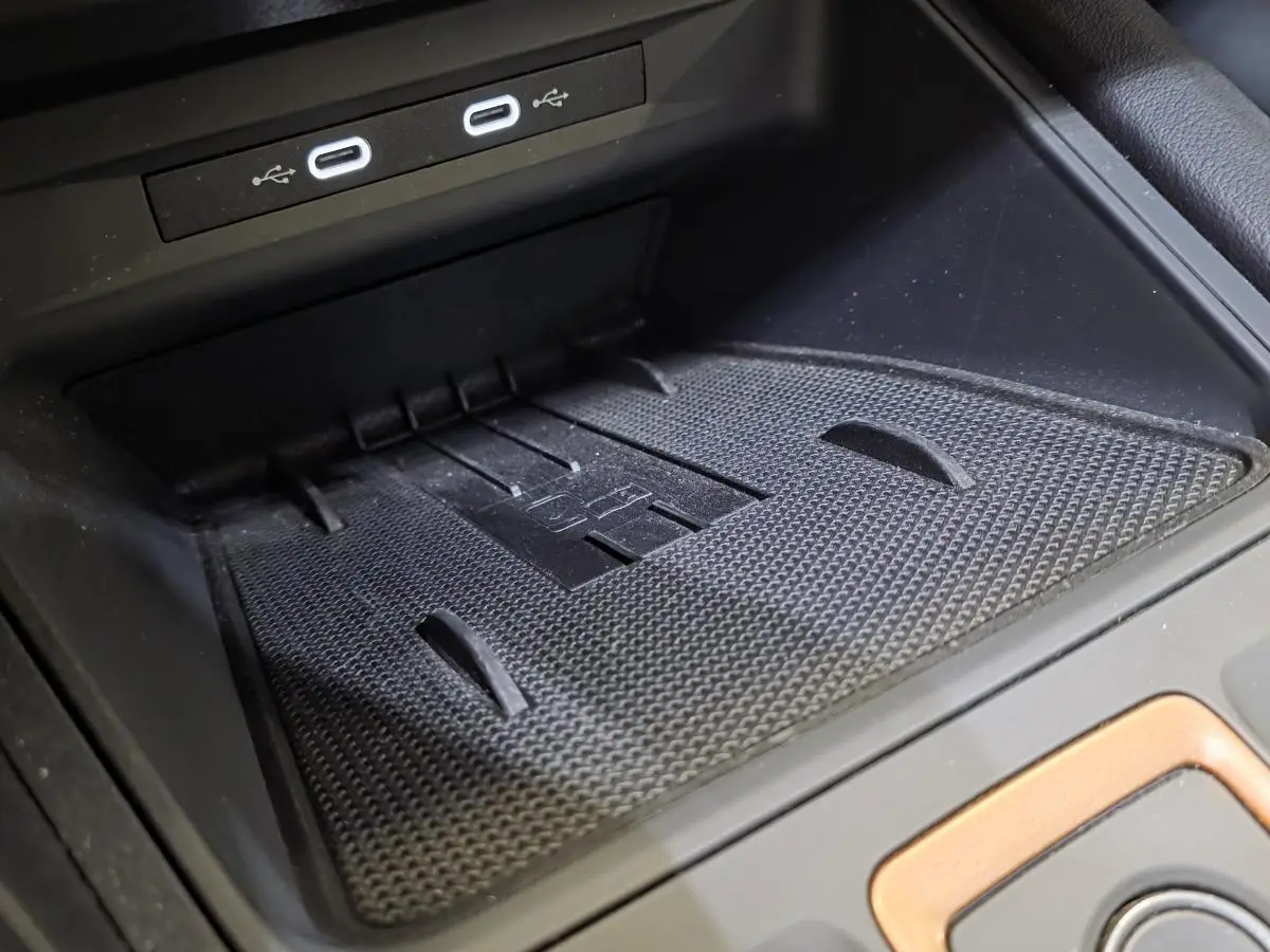 Gros plan sur la zone de charge sans fil noire avec ports USB-C dans l’habitacle du CUPRA Formentor blanc.