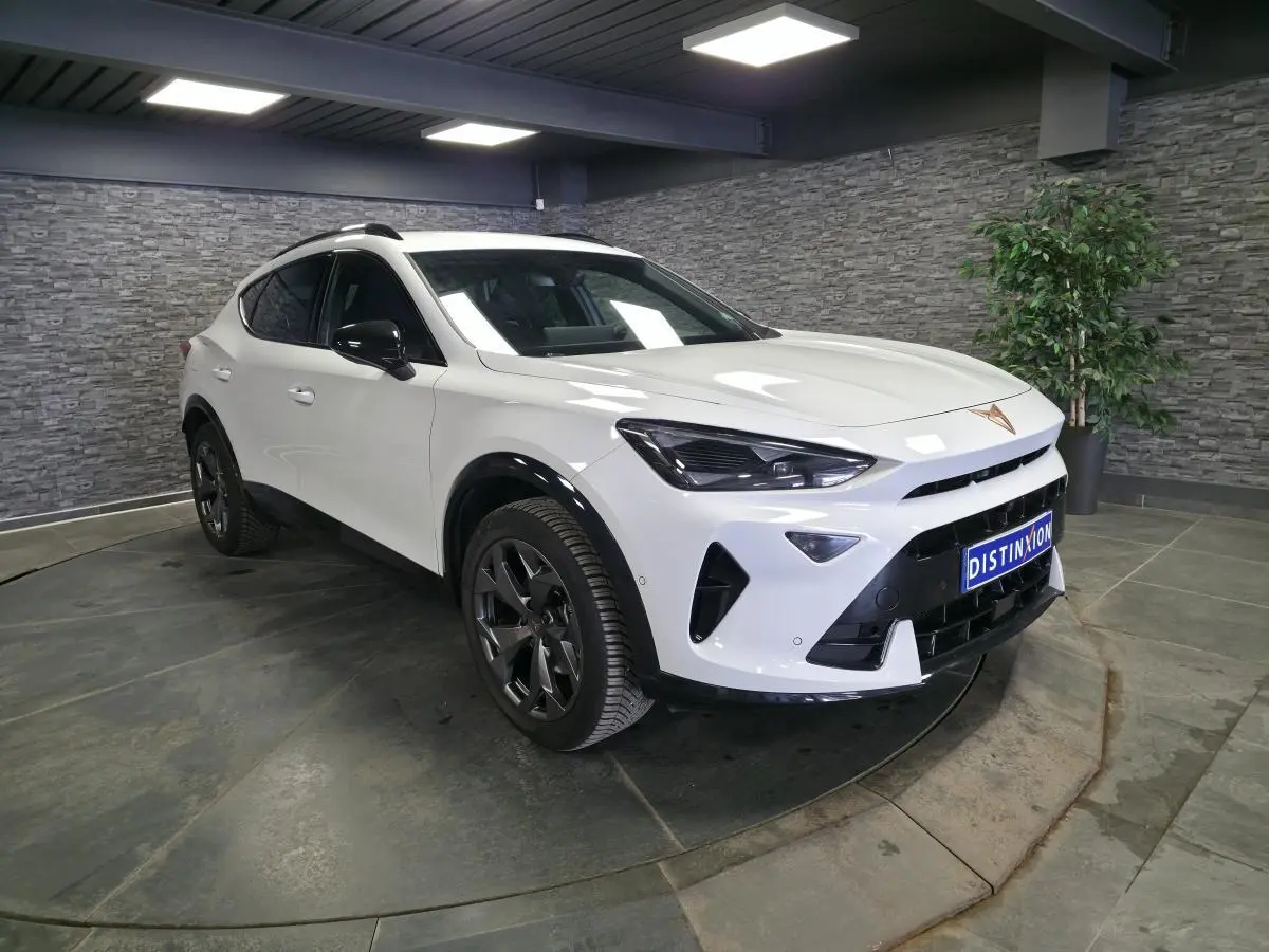 Vue 3/4 avant droite du CUPRA Formentor blanc avec jantes noires et détails noirs contrastants en intérieur showroom.