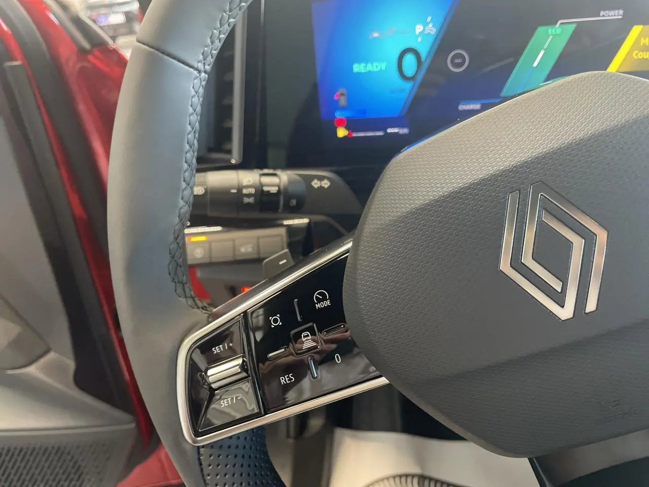 Gros plan sur le volant gris textile du Renault Rafale 2025, avec commandes intégrées et tableau de bord digital en arrière-plan.