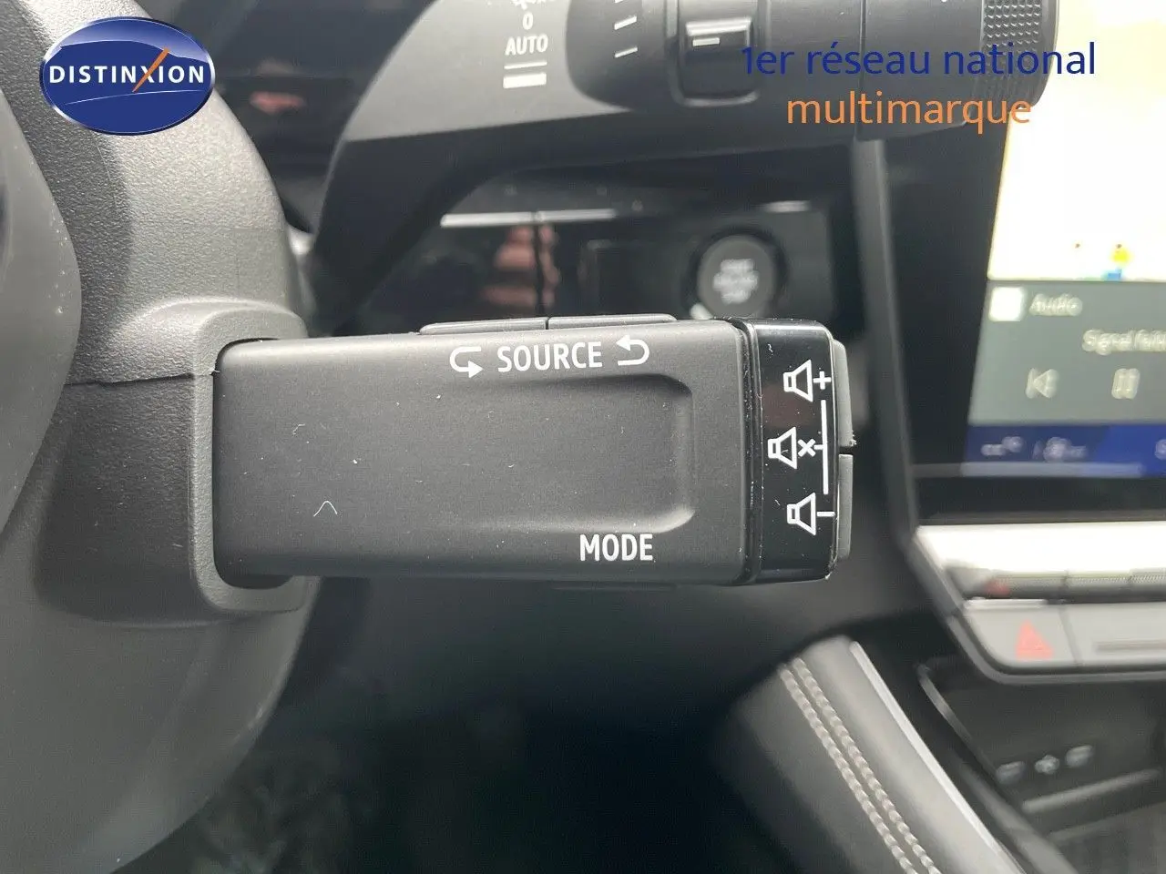 Gros plan sur la commande au volant du Renault Austral blanc nacré 2024, mettant en valeur les fonctions source et mode audio.