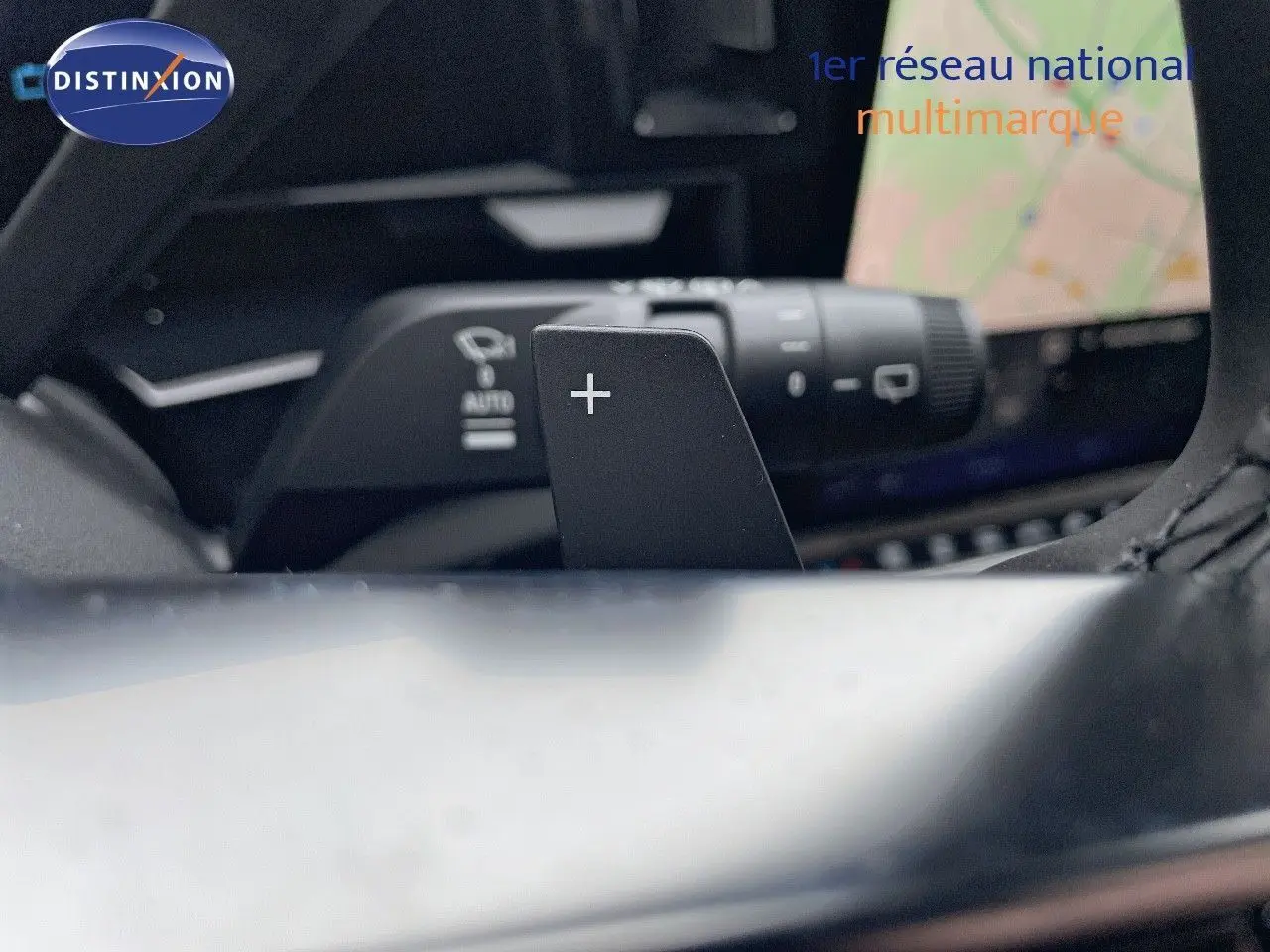 Gros plan sur la palette de changement de vitesse droite du volant du Renault Austral blanc nacré 2024 avec écran tactile en arrière-plan.