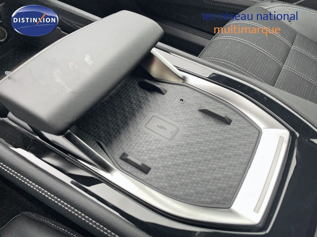 Gros plan sur le chargeur sans fil et l'accoudoir central du Renault Austral E-Tech blanc nacré, intérieur tissu gris.