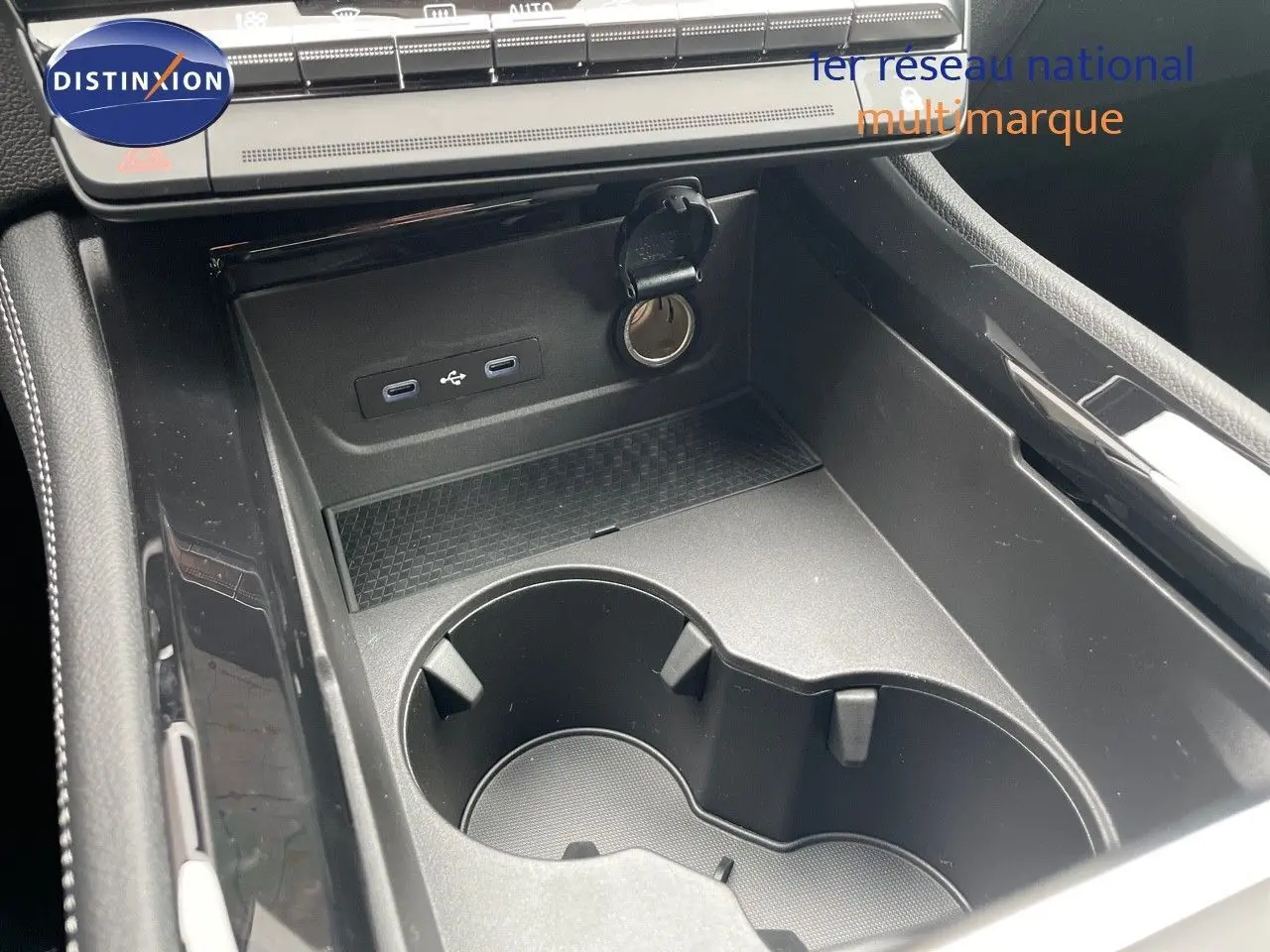 Gros plan sur la console centrale noire du Renault Austral 2024, avec porte-gobelets et prises USB visibles.