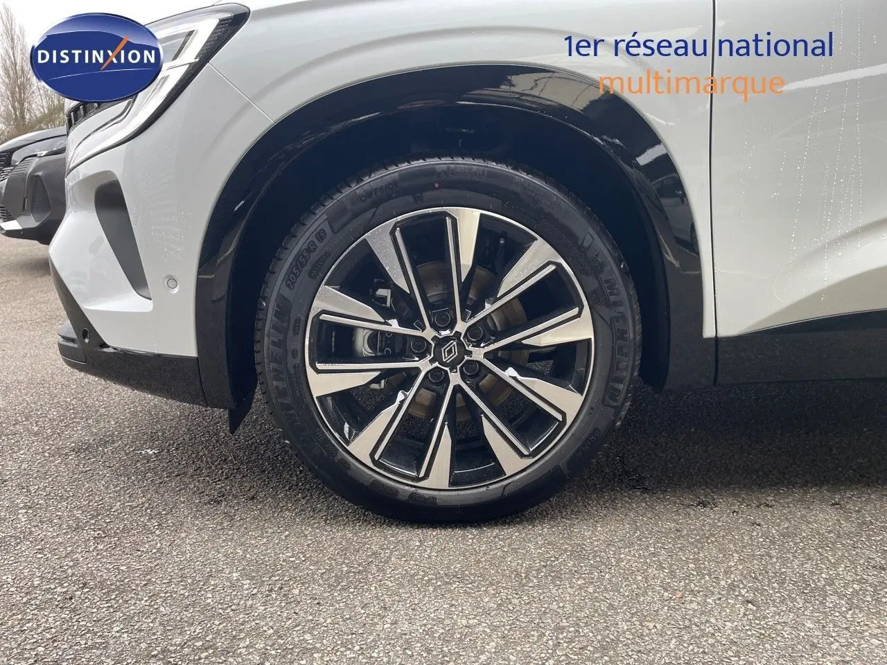 Gros plan sur la roue avant gauche du Renault Austral blanc nacré avec jante bi-ton et logo central Renault.
