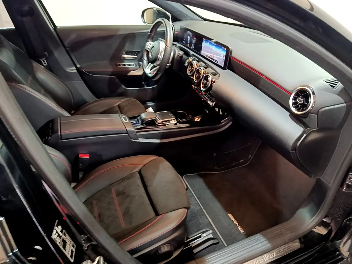 Intérieur noir de la Mercedes Classe A 180 AMG Line 2019, vue côté passager avec tableau de bord et sièges sport rouges.