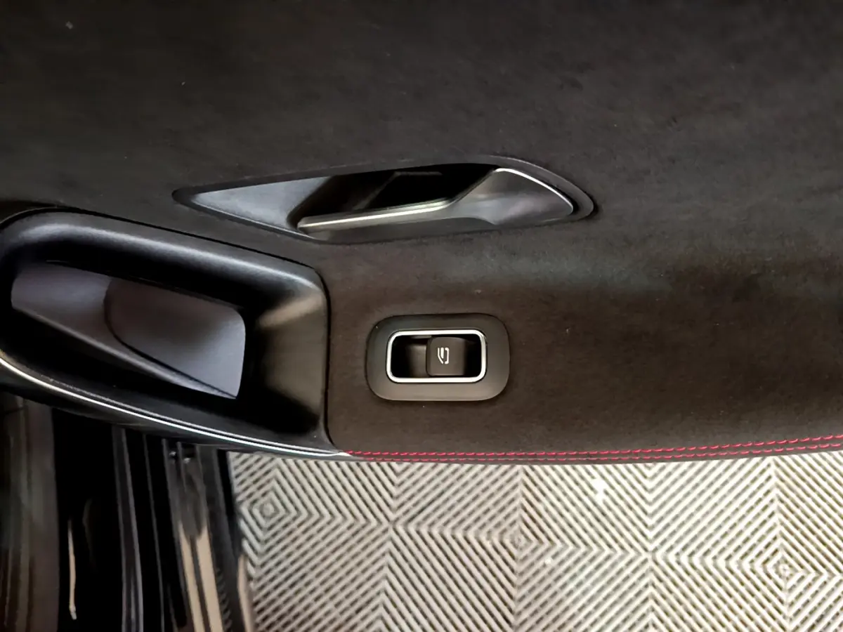 Détail de la poignée intérieure noire avec bouton de verrouillage sur la porte côté gauche d'une Mercedes Classe A 180 AMG Line noire.