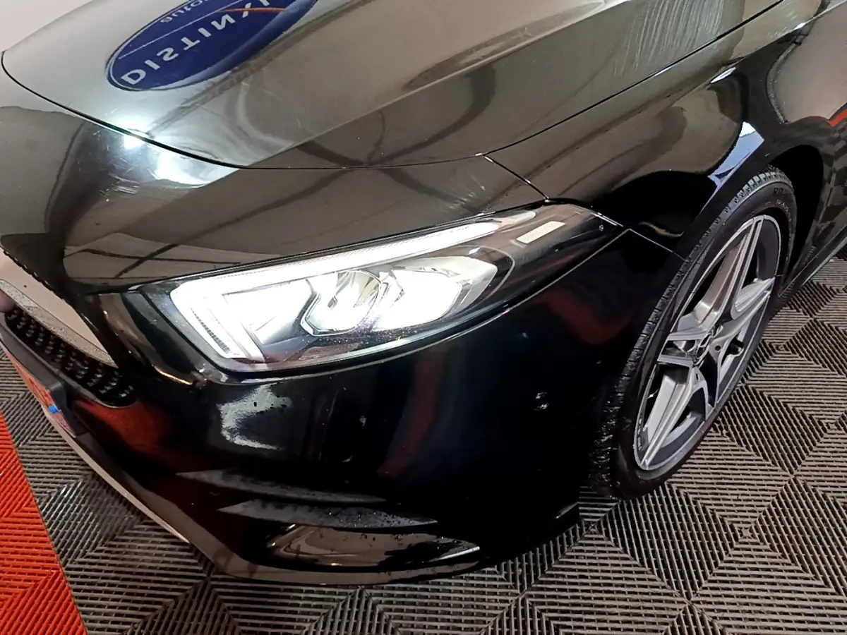 Gros plan sur l'avant droit noir brillant d'une Mercedes Classe A 180 AMG Line, mettant en valeur le phare LED et la jante alliage.