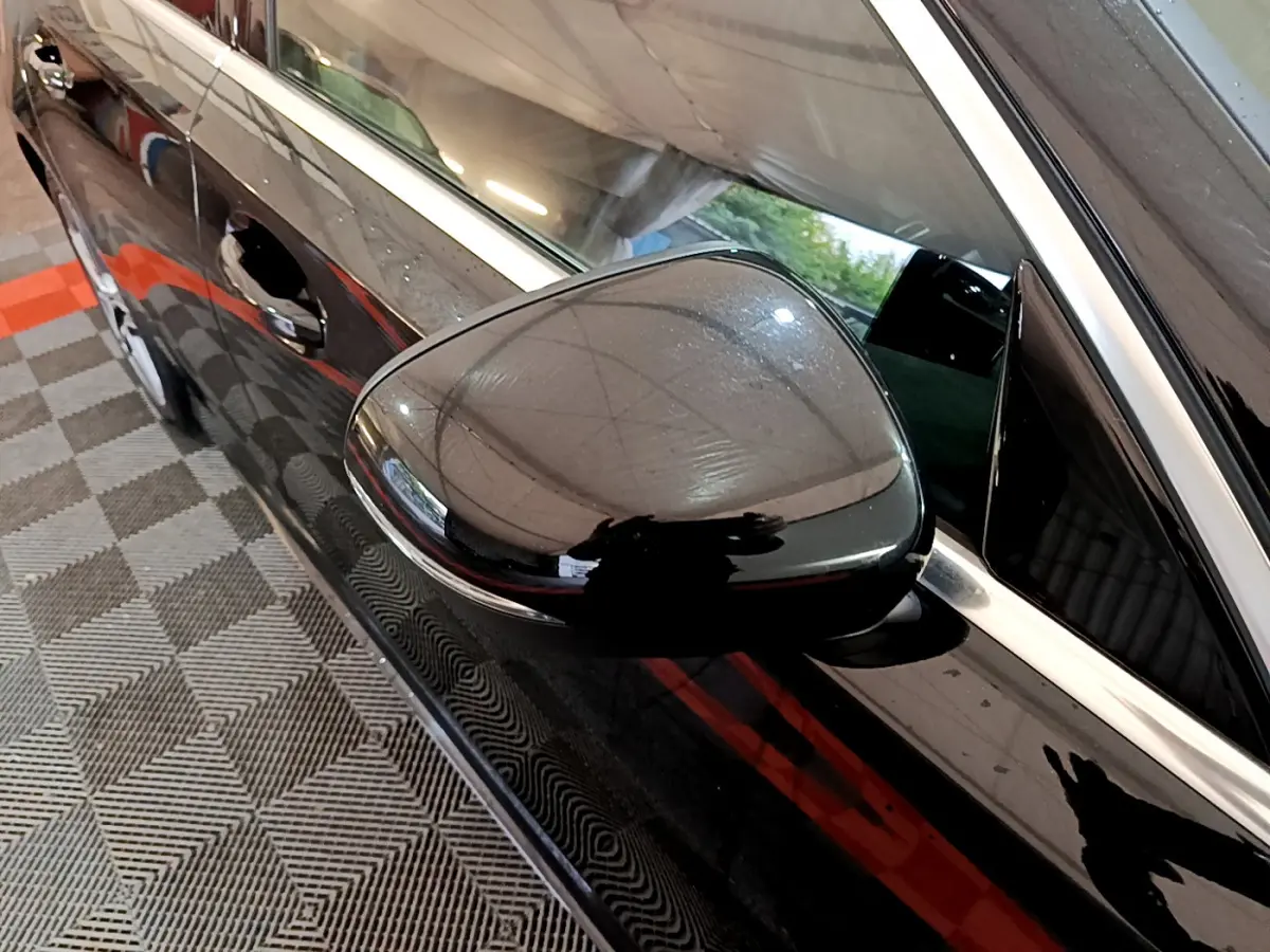 Gros plan sur le rétroviseur côté gauche noir brillant d'une Mercedes Classe A A 180 AMG Line noire, vue latérale.